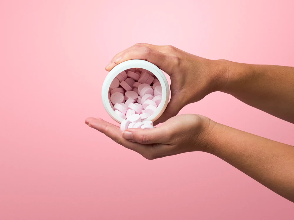 Creatine capsules poured from a container into an open hand