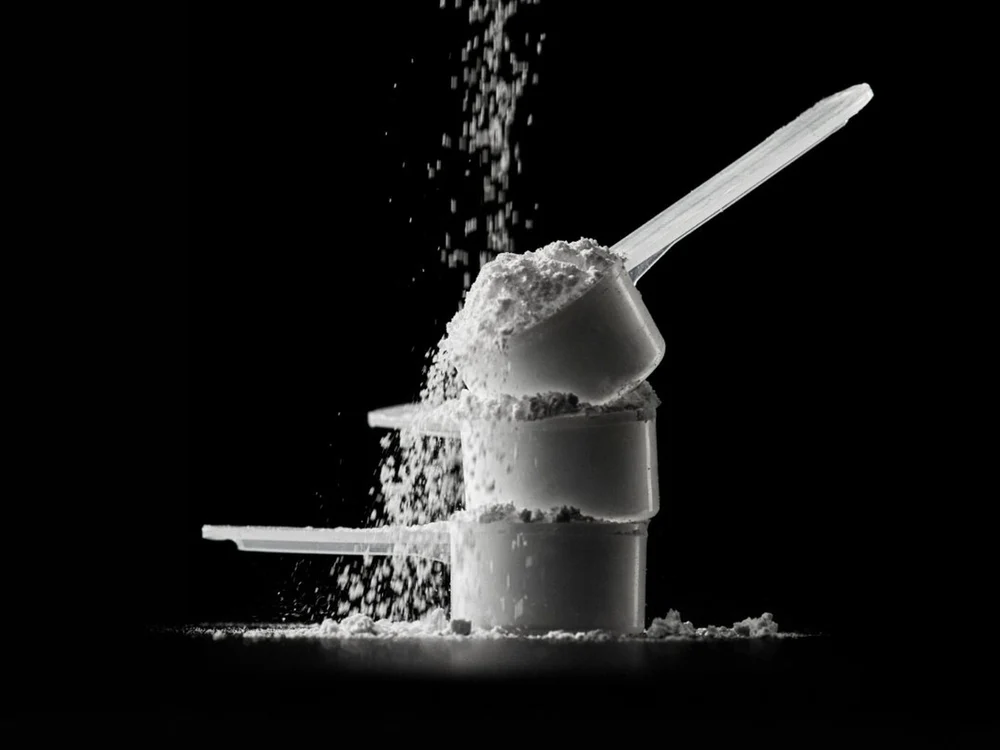 Stacked scoops of creatine monohydrate powder against a black background